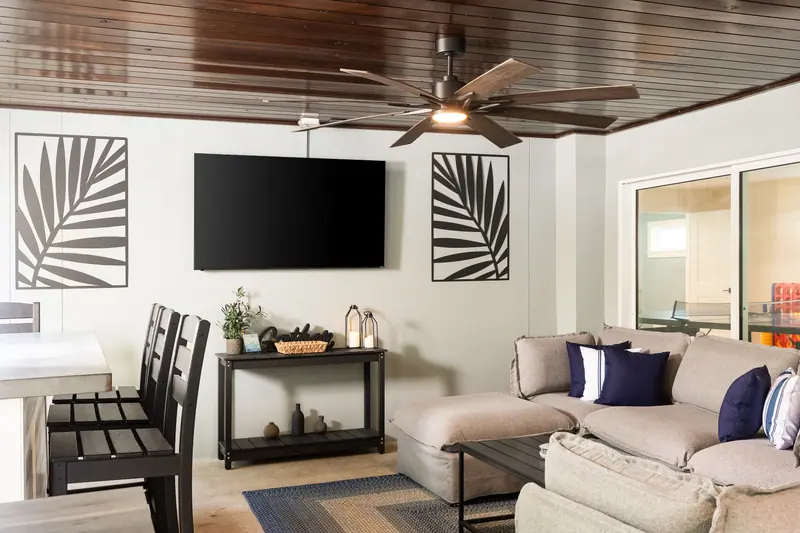 Covered lounge with large sectional, dining space and wall-mounted TV