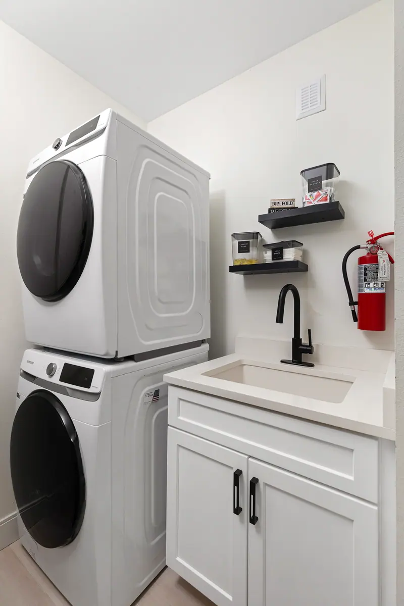 Laundry room with high-efficiency washer and dryer, deep sink and stocked supplies